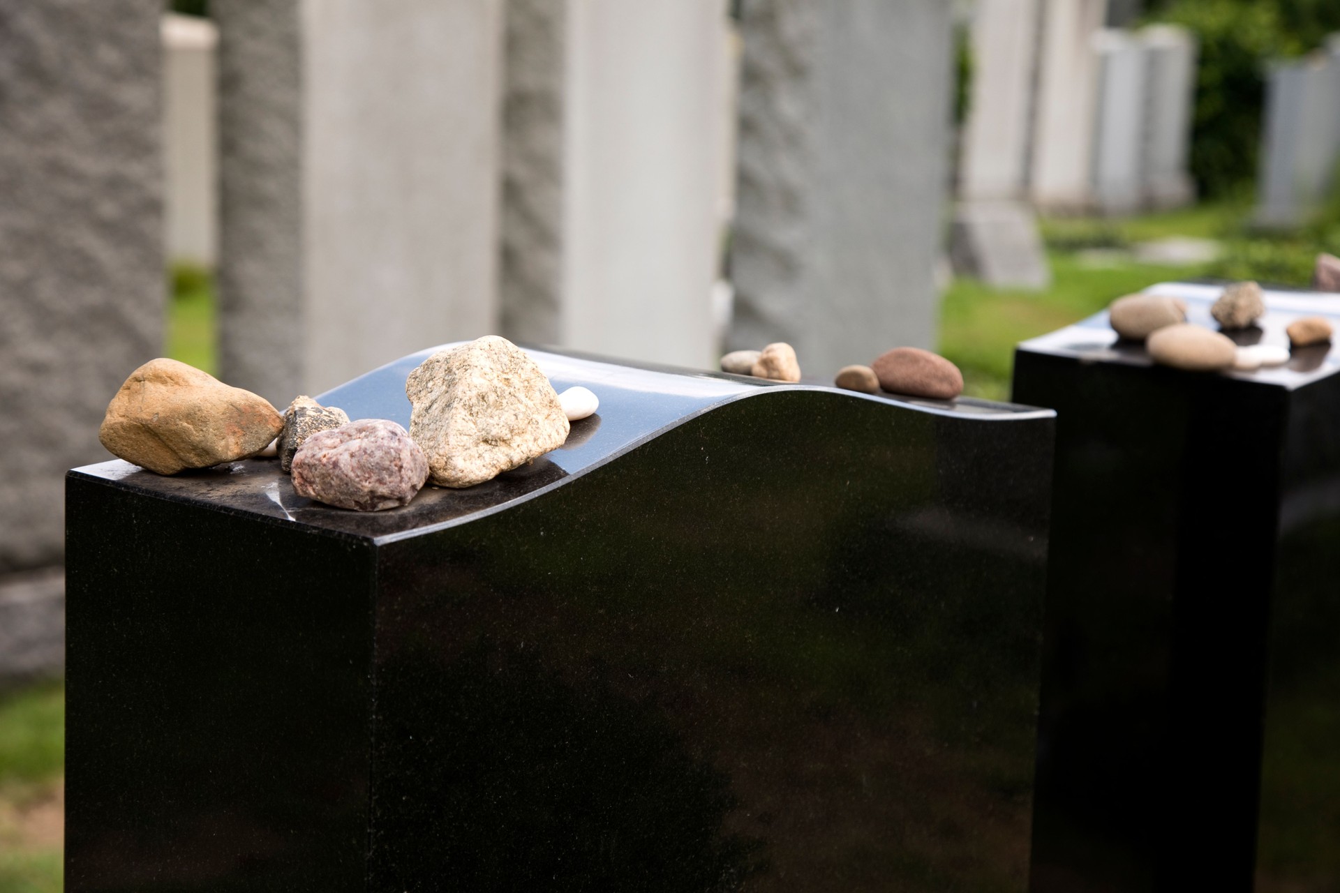 Mourning rocks on a black granite gravestone in Jewish cemetery